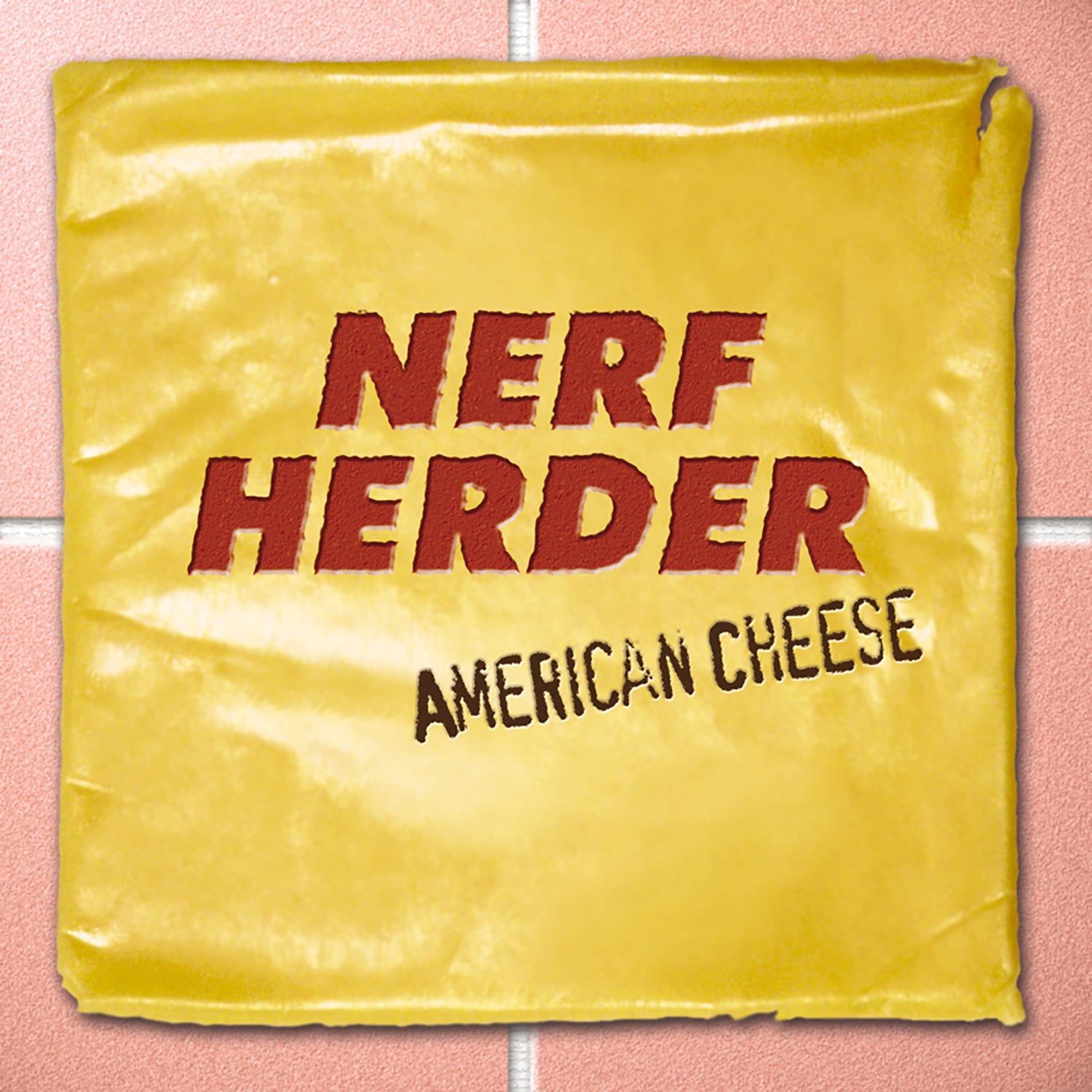 A slice of American cheese with NERF HERDER and AMERICAN CHEESE printed in bold, red, and black letters—resembling the quirky cover of a Nerf Herder album—rests on a tiled surface.