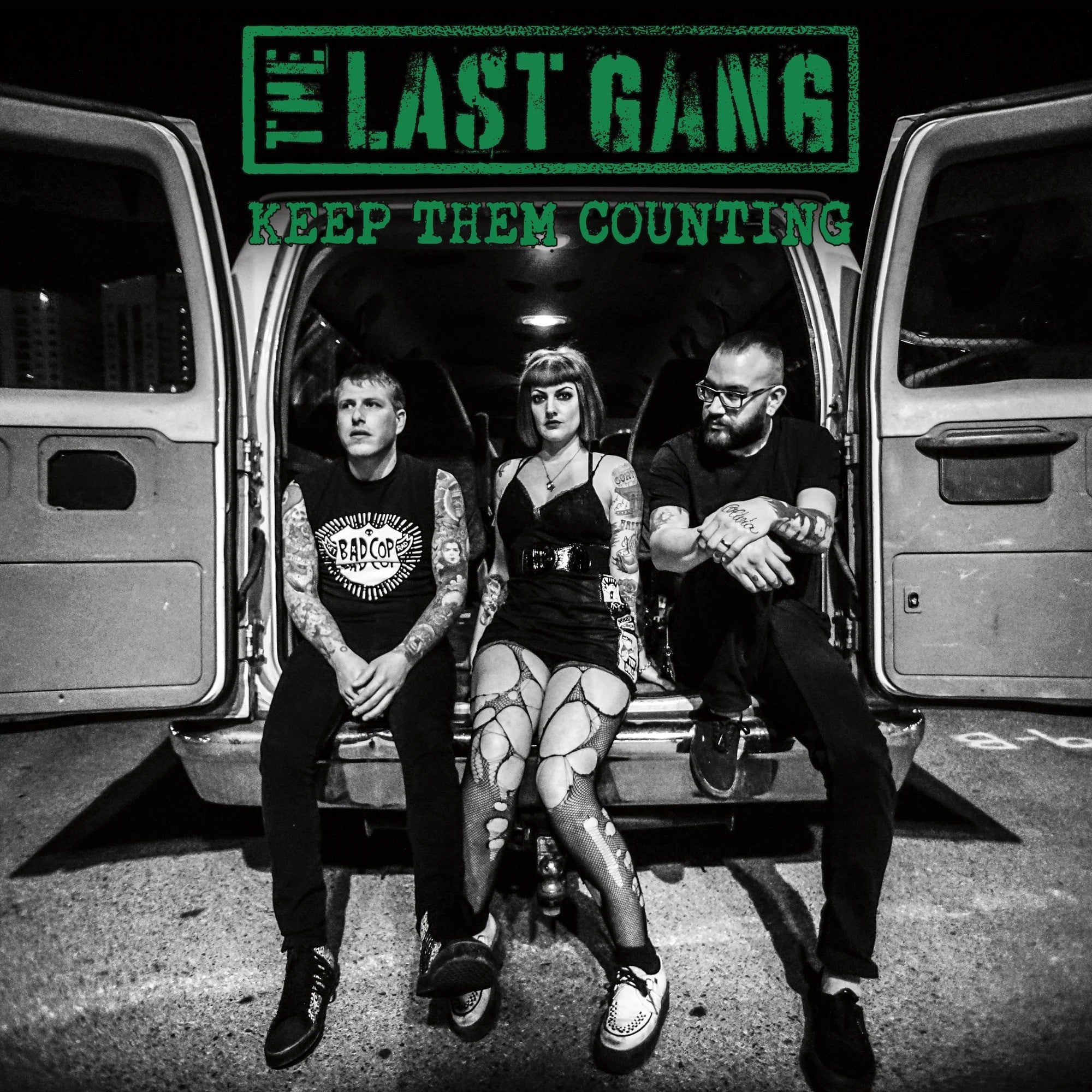 Three tattooed band members sit on a vans open back at night. Overhead, bold green text reads “THE LAST GANG”—their debut full-length album. The black and white photo channels classic black vinyl LP style. Brand Name: The Last Gang.